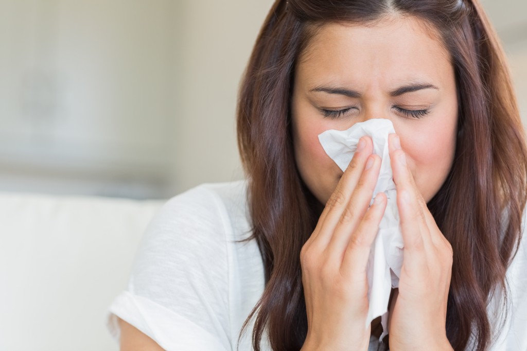 Burnette woman blowing nose into tissue